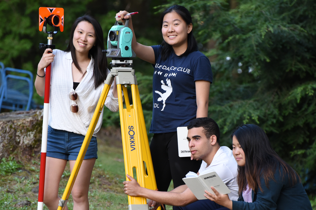 Four students using land surveying tools