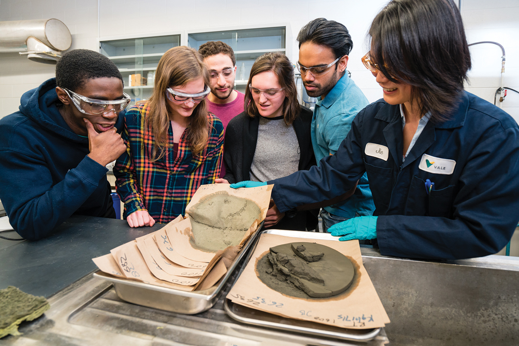 Five students and an instructor looking at samples.