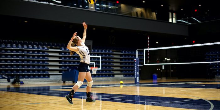 Varsity volleyball player Kate Lonergan serves the ball.