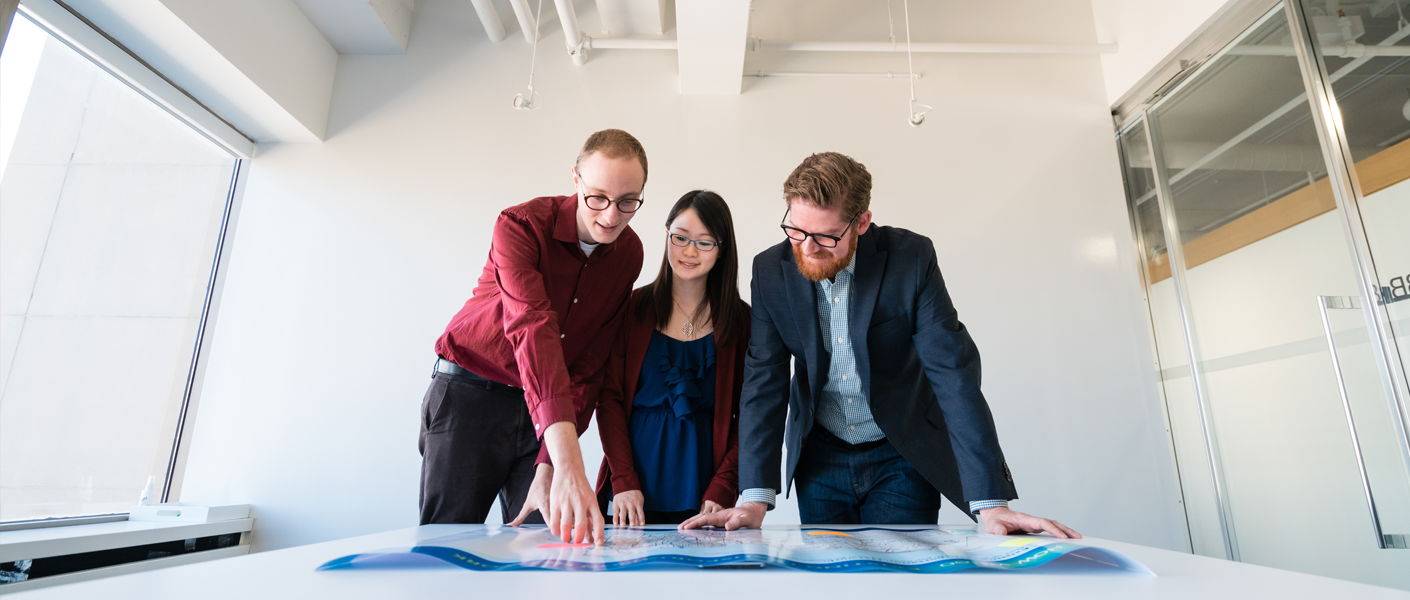people standing over blueprints on a desk