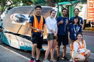 A group of students stand in front of a solar car.