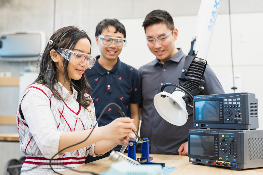 Three students using electrical equipment.