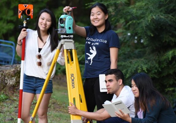 Four students using land surveying tools